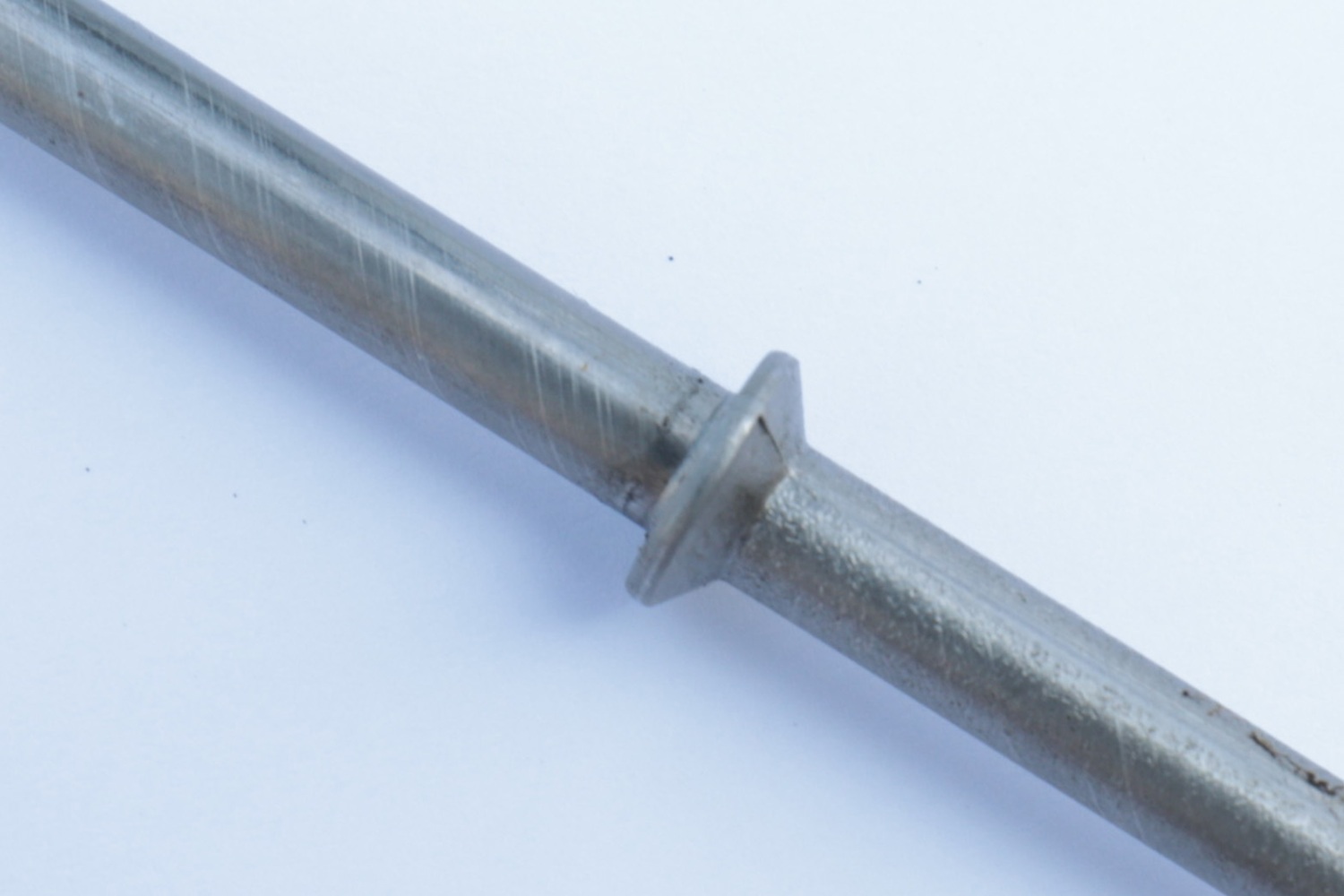 Close-up of a metal rod with an integral collar produced by cold upsetting